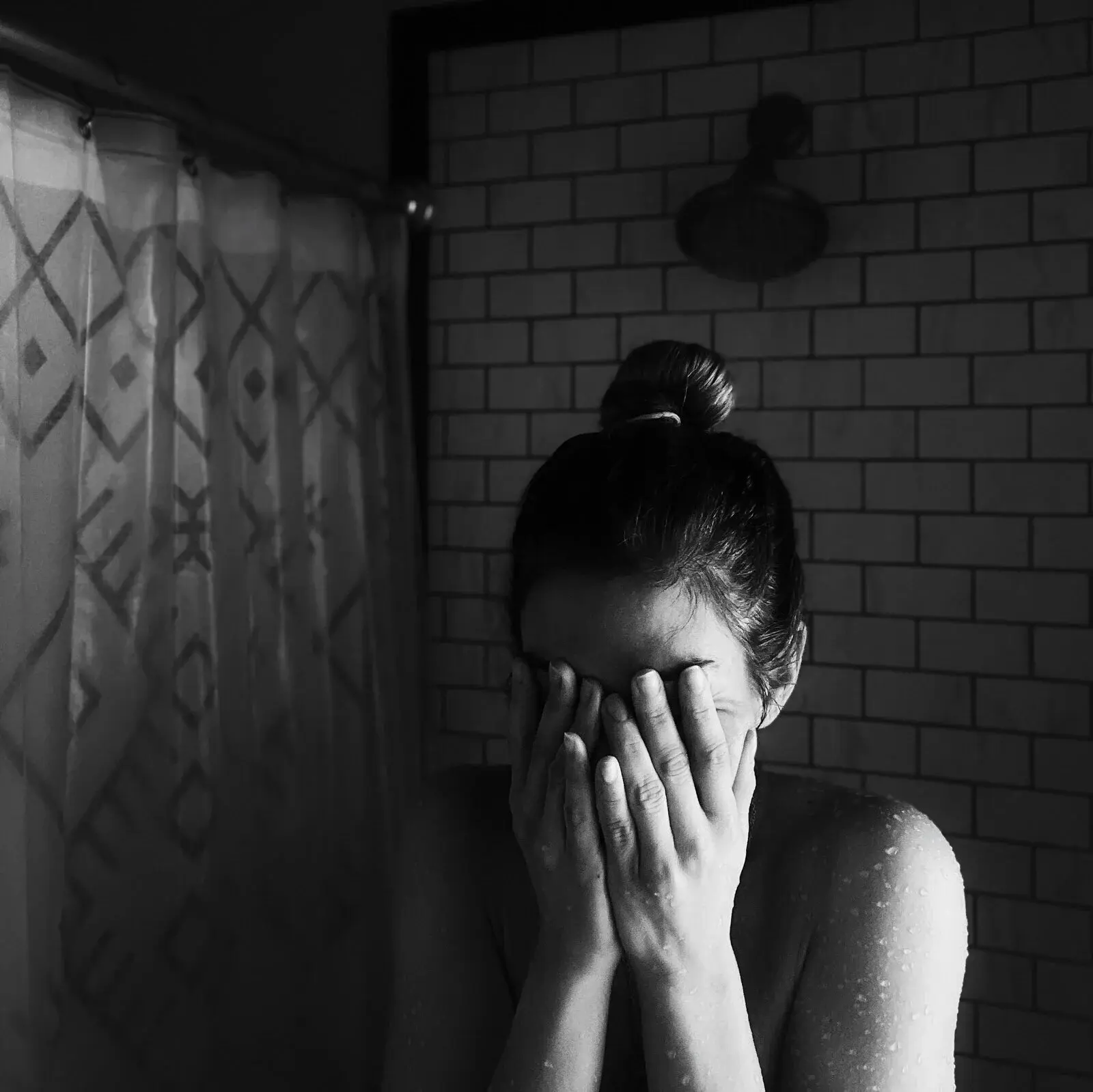 Photo en noir et blanc d’une jeune mère sous la douche pendant le post-partum